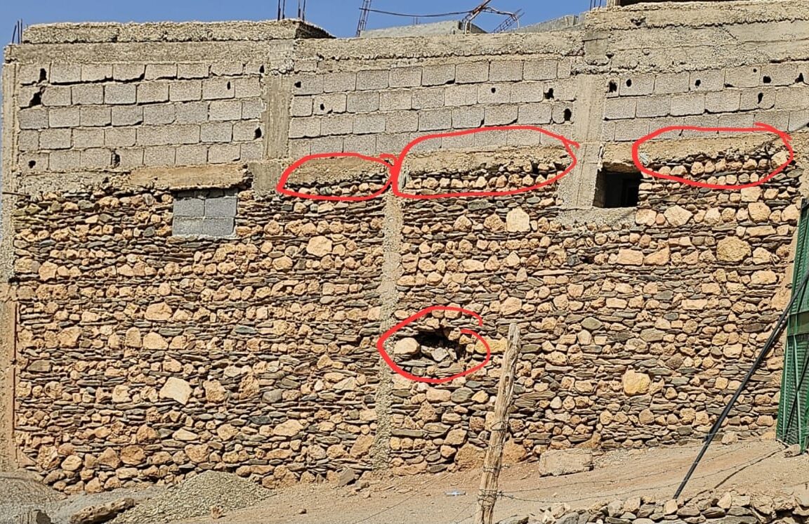 A stone wall with red circles on it Description automatically generated